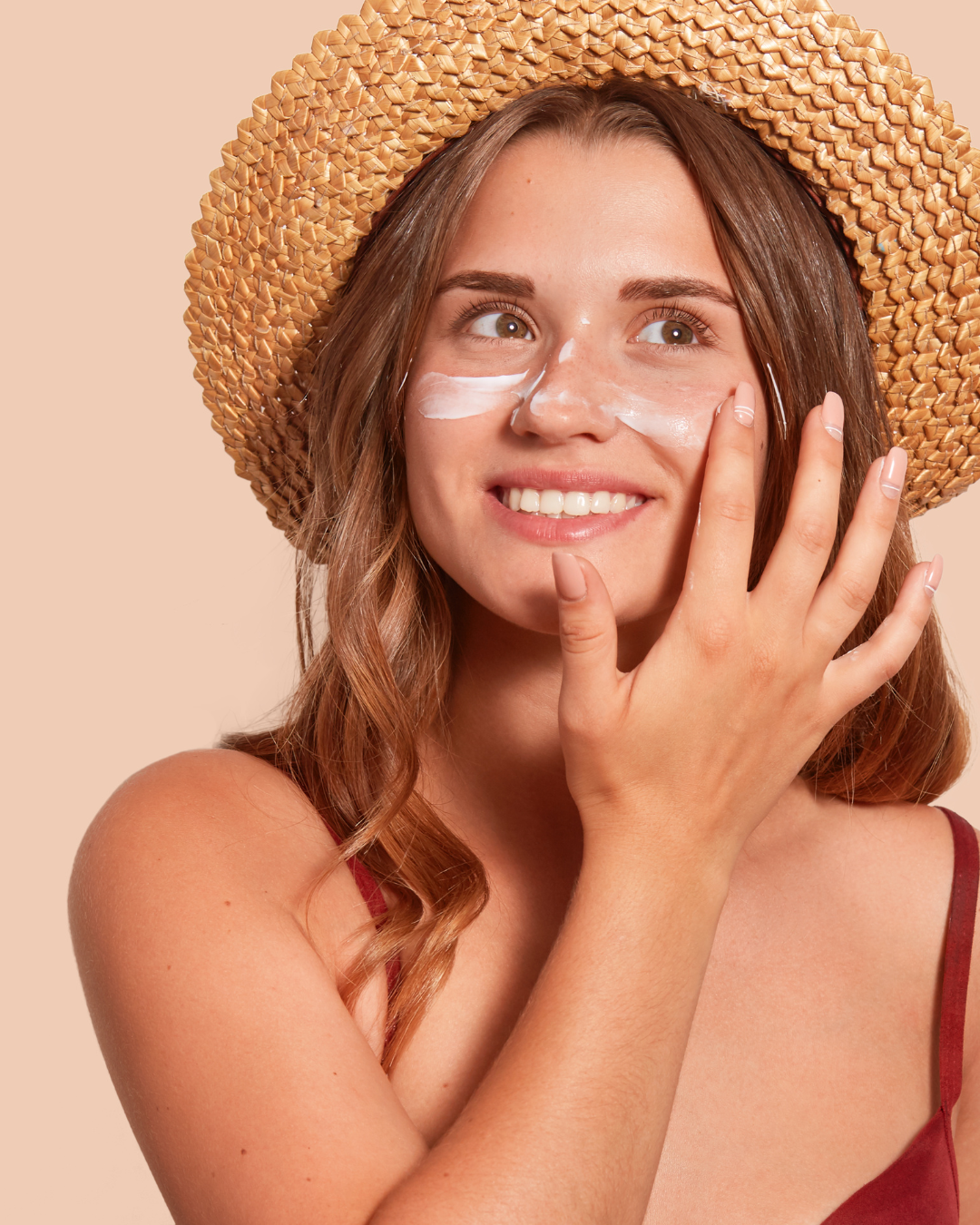 Ragazza che si mette la crema solare con un cappelli di paglia